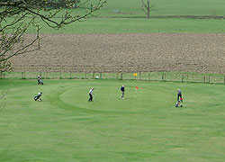 A photograph of golfers on the green at Avro Golf Club near Woodford in Cheshire